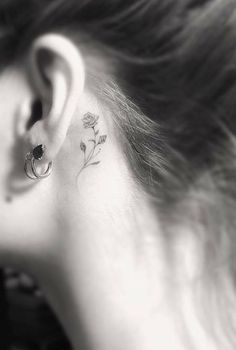 a woman's ear has a small flower tattoo on it, behind her ear