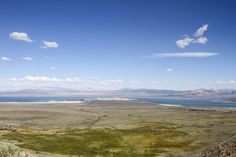 an open field with water and mountains in the background