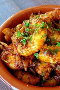 a bowl filled with cooked shrimp and garnished with parsley on the side