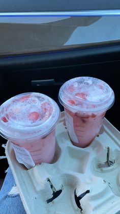 two plastic cups filled with pink liquid sitting on top of a white tray next to each other