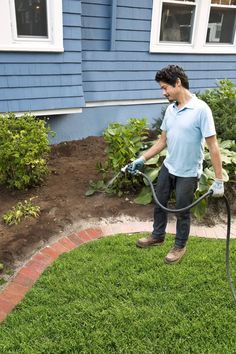 a man is using a pressure washer to clean the grass in front of his house