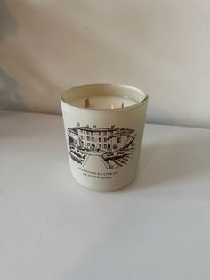 a candle that is sitting on top of a white tablecloth with an image of a building in the background