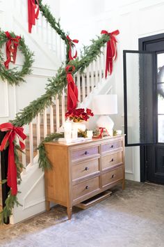 christmas decorations on the banisters and stairs in a house with red bows hanging from them