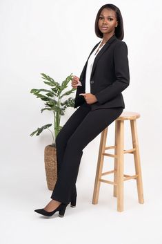 a woman sitting on top of a stool next to a potted plant