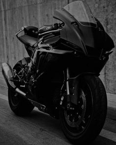 black and white photograph of a motorcycle parked on the side of the road in front of a concrete wall