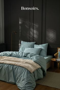 an image of a bedroom setting with blue sheets and comforter on the bed in front of a black wall