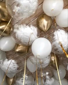 white and gold balloons are hanging from the ceiling in front of wooden planked walls