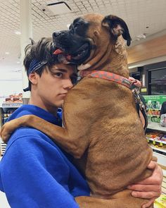 a man holding a dog in his arms at the grocery store while wearing headbands