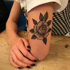 a woman's arm with a black and white rose tattoo on her left side