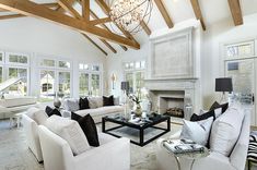 a living room filled with white furniture and a chandelier hanging from the ceiling