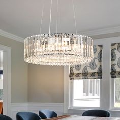 a chandelier hanging from the ceiling in a dining room with blue chairs around it