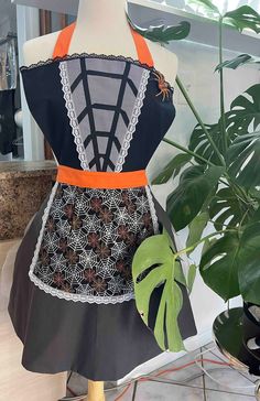 a mannequin with an apron on top of it next to a potted plant