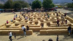 many people are standing in front of a large maze made out of straw bales