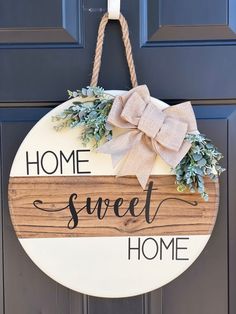 a wooden sign that says home sweet home hanging on a front door with a bow