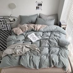 an unmade bed in a room with black and white checkered flooring