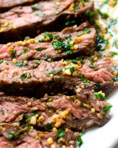 steak with herbs and seasoning sitting on a white plate, ready to be eaten