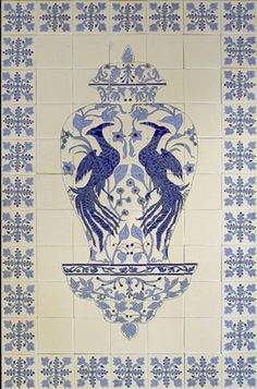 a blue and white tile wall with two birds on the top, surrounded by floral designs