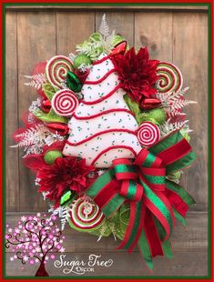 a christmas wreath with candy canes and a tree on the front door for decoration