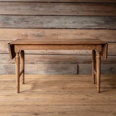 an old wooden table sitting on top of a hard wood floor next to a wall