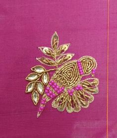 a pink and gold broochle with leaves on it, sitting on top of a purple