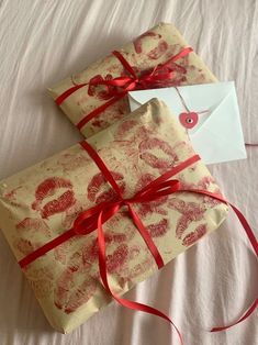 two wrapped presents with red ribbon on white sheets