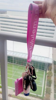 someone holding up a pink lanyard with several keys hanging from it