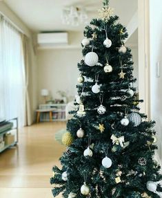 a small christmas tree in the middle of a room with white and gold ornaments on it