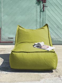 a green bean bag chair sitting on top of a cement floor next to a door