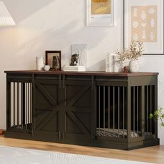 a dog crate is sitting on the floor in front of a wall with framed pictures