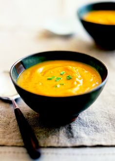 two black bowls filled with soup on top of a table