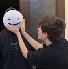 a young man is holding up a smiley face mask