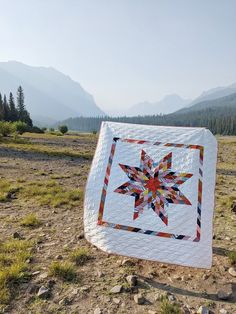 a quilted star on the ground with mountains in the background