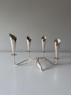 four silver candlesticks sitting on top of a white table