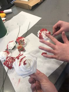 someone is decorating cupcakes with white frosting and red decorations on them