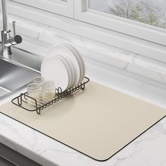 a dish rack with plates and glasses in front of a sink