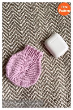 a pink knitted mitt next to a white object on a brown and white blanket