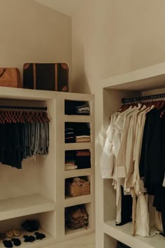 an open closet with clothes and shoes on the shelves, next to a handbag