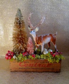 a deer figurine sitting on top of a wooden box next to a christmas tree