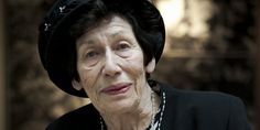 an older woman wearing a black hat and pearls