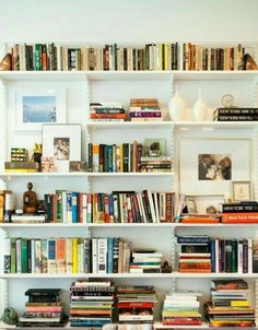 a bookshelf filled with lots of books next to a dining room table and chairs