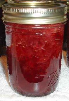 two jars filled with red liquid sitting on top of a white cloth covered tablecloth