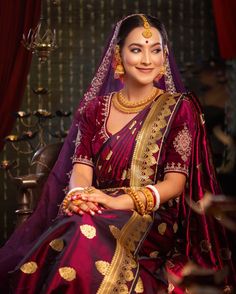 a woman in a red and gold bridal outfit sitting on a chair with her arms crossed