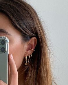 a close up of a person holding a cell phone in front of their face and wearing earrings