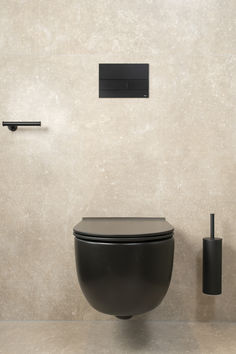 a black toilet sitting next to a wall mounted faucet