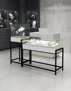 two tables with glass cases on them in a room filled with white and black items