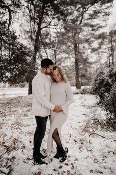 a pregnant couple standing in the snow together