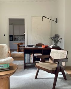 a living room filled with furniture and a painting on the wall next to a chair