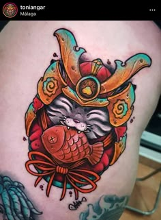 a tattoo with an image of a cat wearing a hat and holding a fish in it's mouth