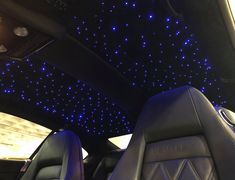 the interior of a car with blue lights on the ceiling and leather seats in front of it