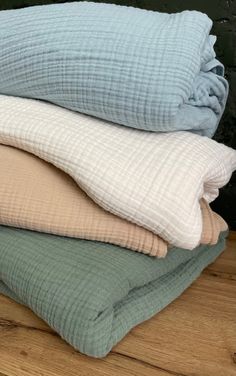 four pillows stacked on top of each other in different colors and sizes, with one folded up